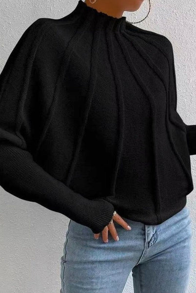 Person wearing a black long-sleeve top and light blue jeans against a plain background