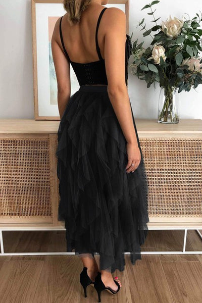 Person wearing a black top with a black tulle skirt in a room with a wooden cabinet and flowers.