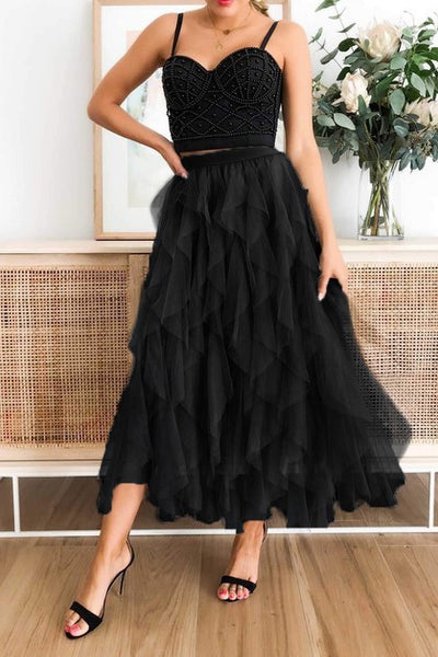 Woman wearing a black top with a black tulle skirt and top in a room with a vase of flowers.
