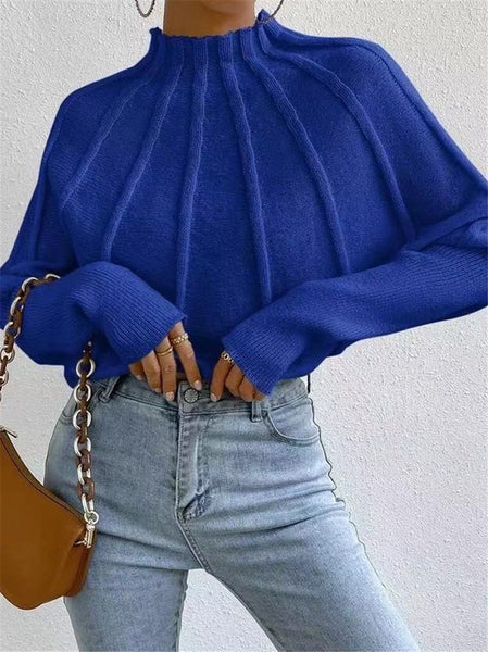 Person wearing a blue sweater and light blue jeans with a brown handbag on a plain background
