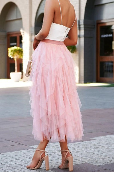 Person wearing a white top and pink tulle skirt on a city street.