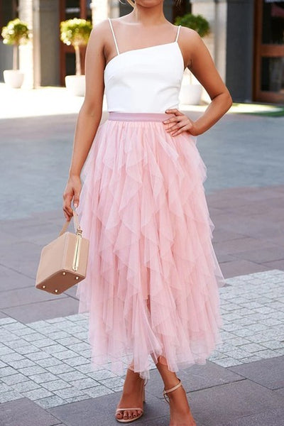 Woman wearing a white top and pink tulle skirt on a city street.