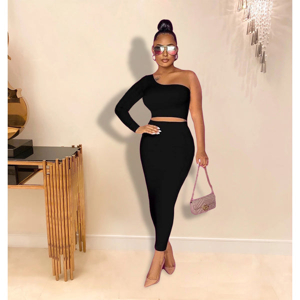 Woman in a black outfit posing indoors with a decorative background