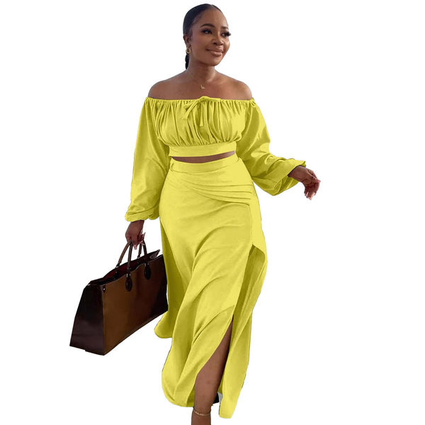 Woman wearing a bright yellow off-shoulder top and skirt set holding a brown bag on a white background