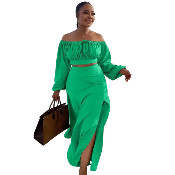 Woman wearing a green off-shoulder top and skirt set holding a brown bag on a white background