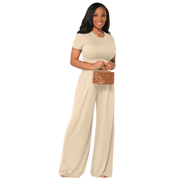 Woman wearing a matching beige top and bottom holding a woven bag on a white background