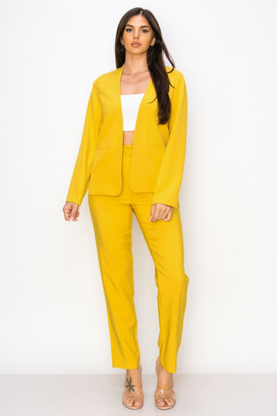 Woman wearing a yellow suit with a white top on a white background