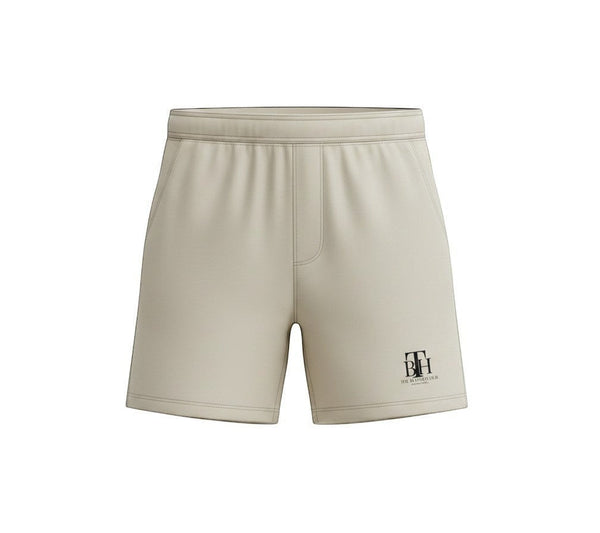 SlayEdgeBoutique beige athletic performance shorts with THE BLESSED HUB INTERNATIONAL logo and elastic waistband.