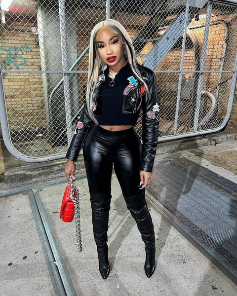 SlayEdgeBoutique black faux leather cropped moto jacket with eclectic patches worn by a model with blonde hair