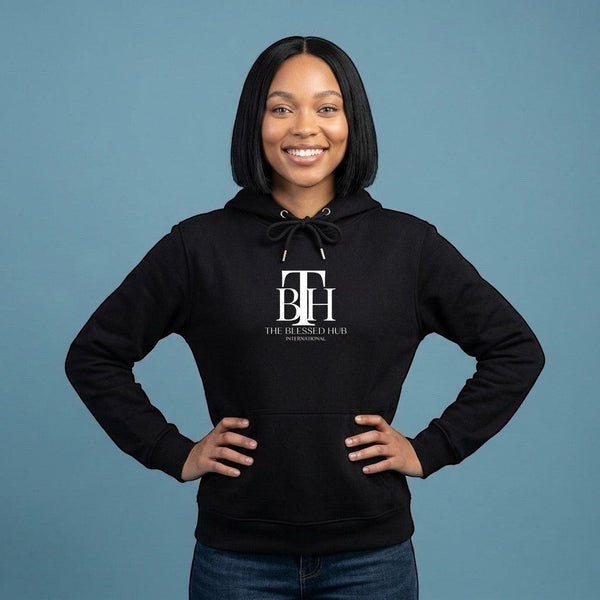 A woman wearing a black SlayEdgeBoutique pullover hoodie with The Blessed Hub International logo on a blue background.