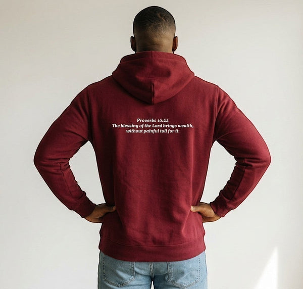 SlayEdgeBoutique maroon pullover hoodie with Proverbs 10:22 scripture printed on the back, worn by a man.