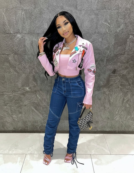 SlayEdgeBoutique pink faux leather cropped moto jacket with eclectic patches worn by a woman with long dark hair.
